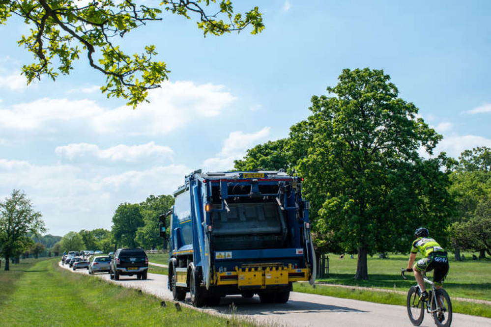 A cyclist behind an HGV and a queue of cars in Richmond Park