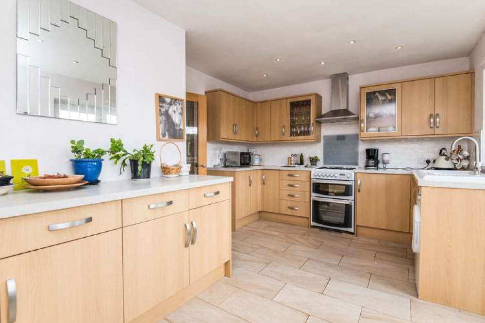 The kitchen has a range of wall and base units, space and connections for appliances, and a white ceramic sink/drainer