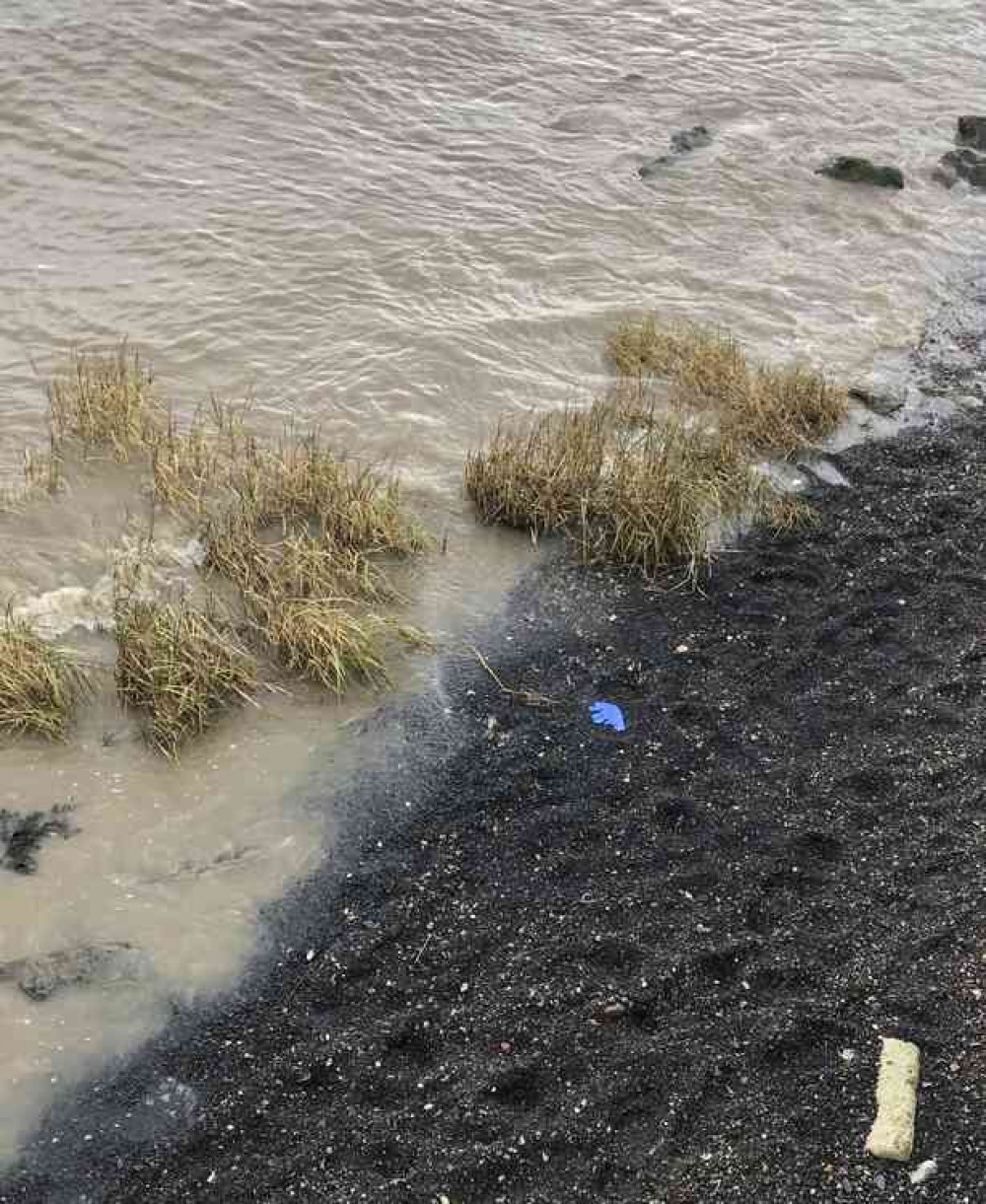 A forensic glove lies on the foreshore as the waves lap closer