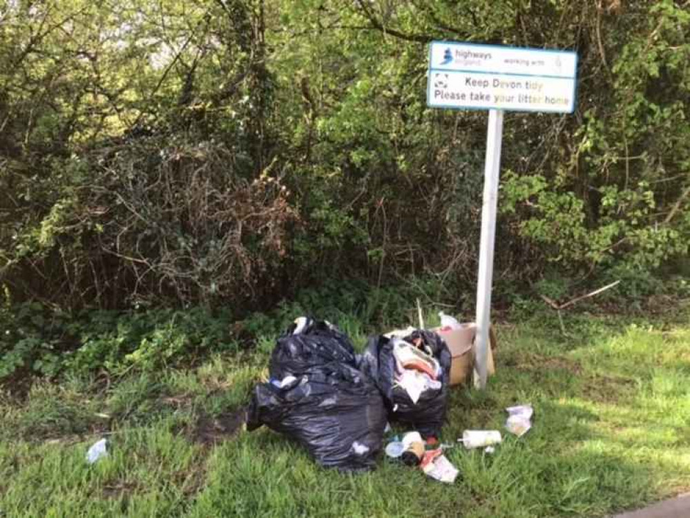 Litter dumped on a roadside at the foot of a Highways England 'Keep Devon tidy' sign Litter dumped on a roadside at the foot of a Highways England 'Keep Devon tidy' sign