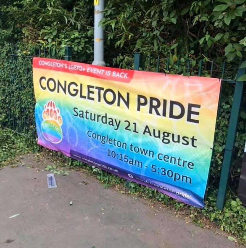 Congleton Pride banner on the railings outside Aldi, secured with wire.