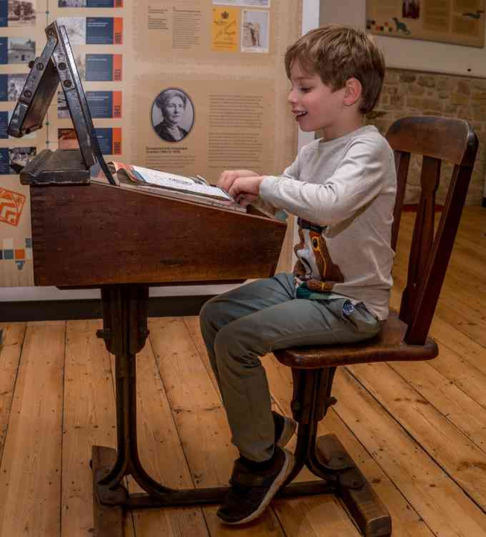 A young visitor enjoying experiencing what school life was like in years gone by