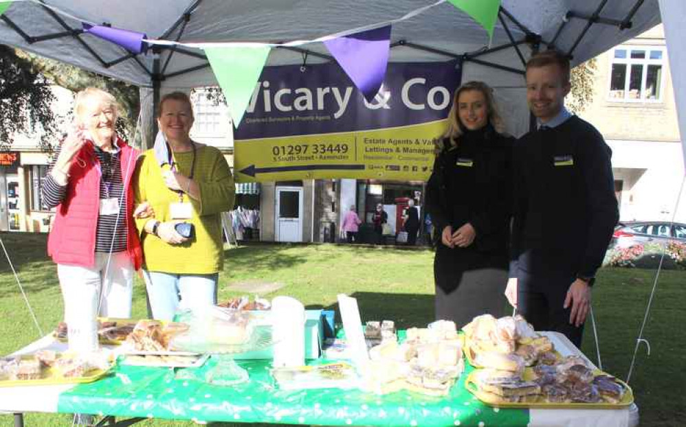 Volunteers from Axminster & Lyme Cancer Support and staff from Vicary & Co at their cake stall on the Minster Green