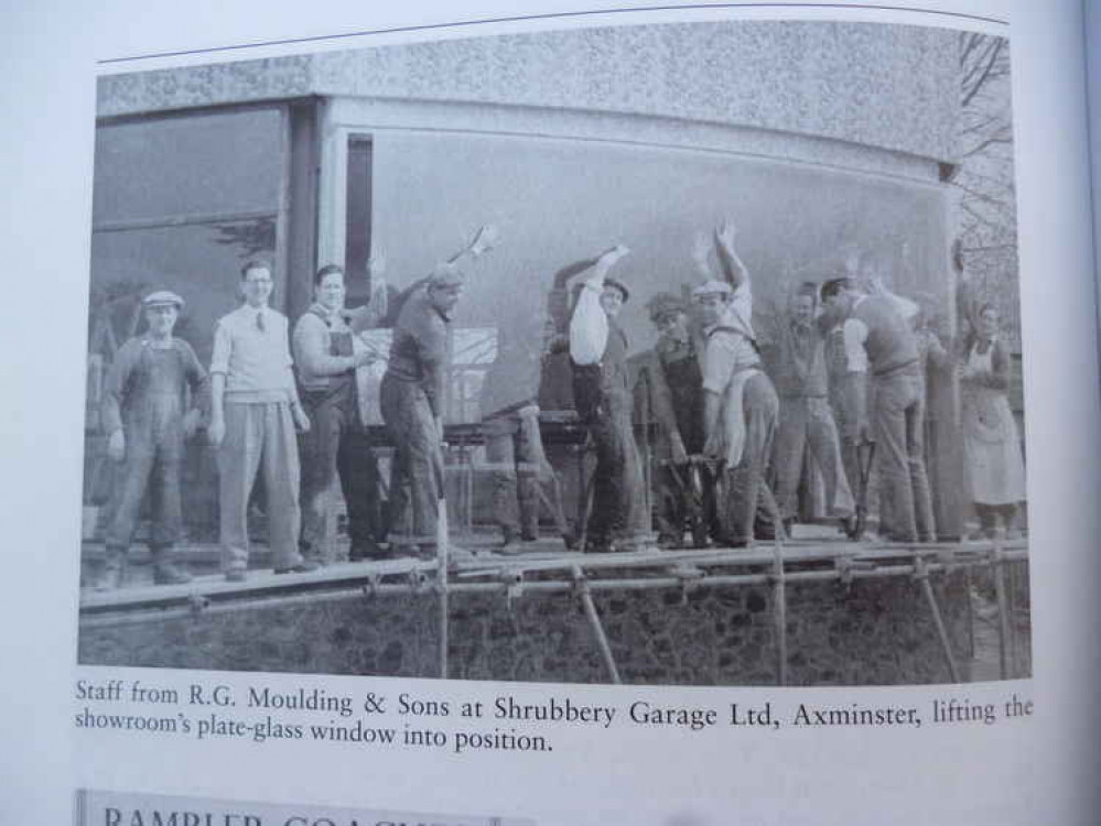 A group of Mouldings employees are placing a huge sheet of plate glass into the window of the Shrubbery Garage in West Street. Tim Moulding is second left