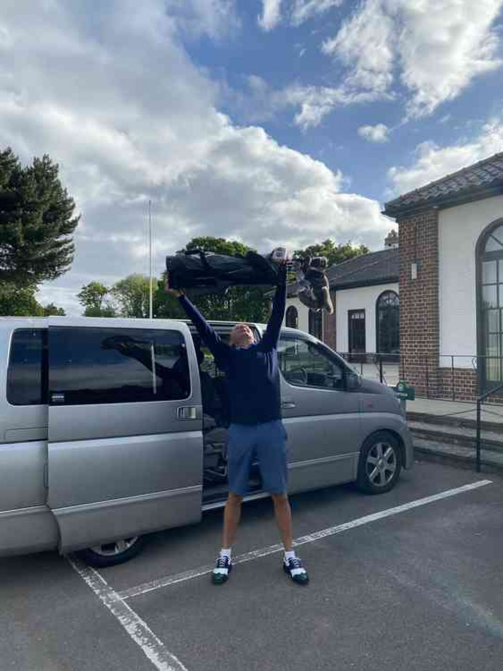 Club captain Nick Adams holds his clubs over his head to celebrate return to the fairways