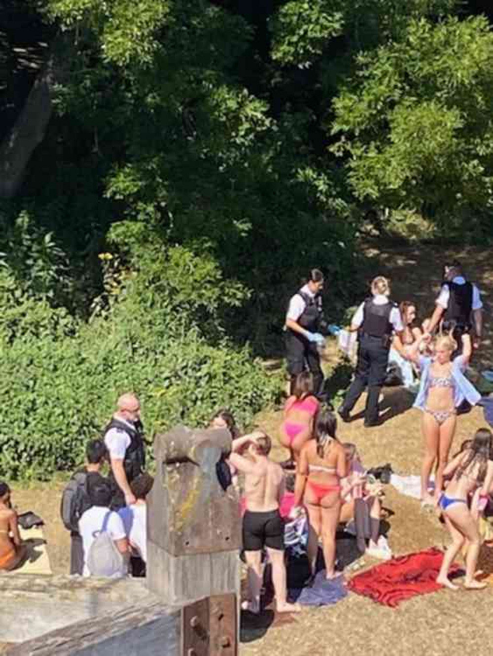 Uniformed police move on the beach area to break up the sunbathers