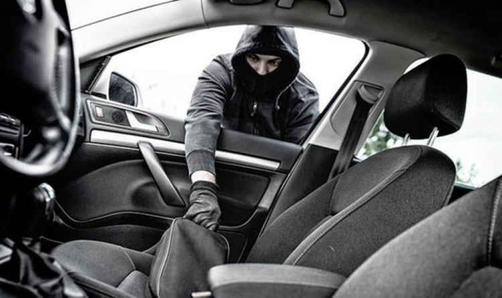 A thief breaking into a car A thief breaking into a car