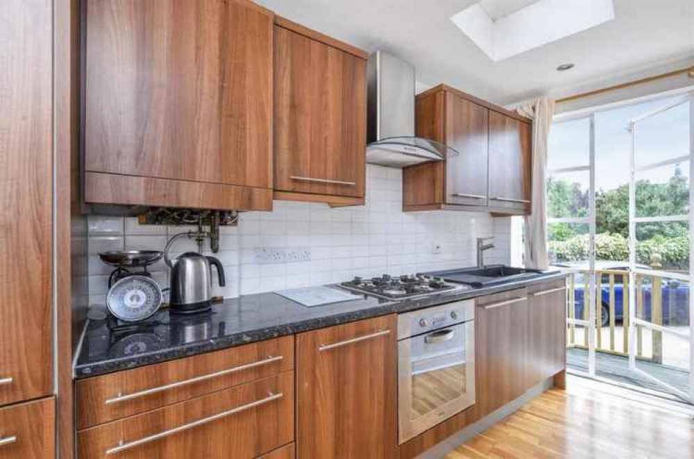 The kitchen has modern-style cabinets and more french doors leading to a small balcony and garden