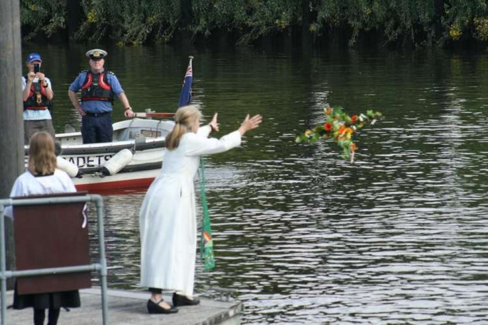 A cross with yellow and orange flowers is tossed into the river as part of the blessing (Credit: Teddington Parish)