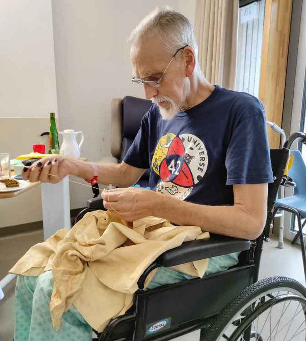 Gareth sewing a prehistoric leather shirt while in the Hospice.