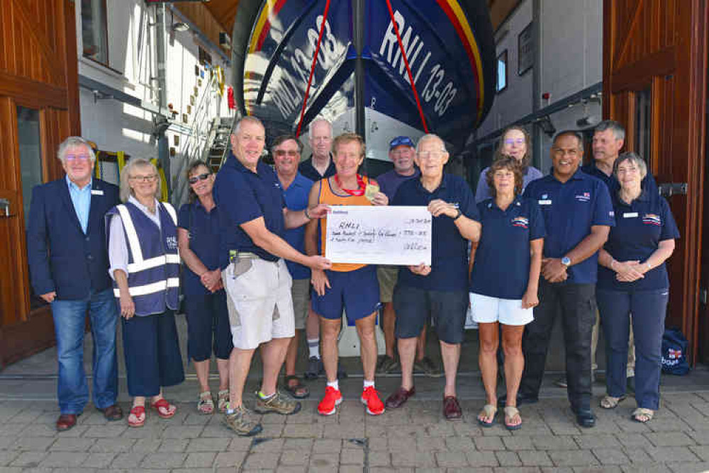 RNLI Tour Guide Des White (centre) proudly holding his London Marathon medal and presenting his cheque to Exmouth Lifeboat Operations Manager, Mike Gall ( left ) and Lifeboat Visits Officer, Bill Lodge ( right ) with fellow Exmouth RNLI Volunteer Tour Gui