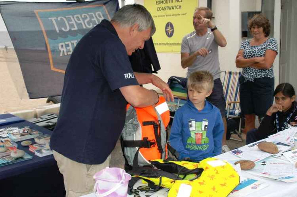 Image: Dave Littlefield from the RNLI Water Safety Team showing six-year-old Rory how to fit his buoyancy aid safely. Credit: David Wright