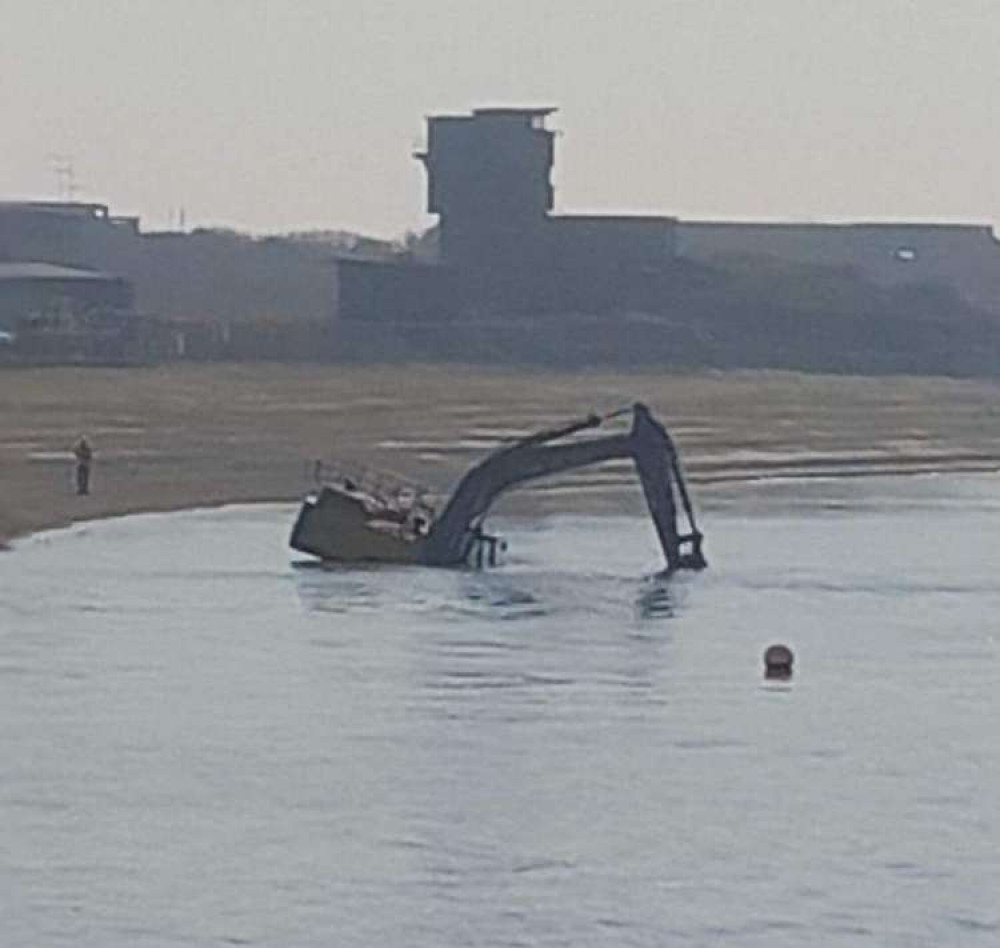 Contractor on beach as digger is getting submerged (Picture contributed)