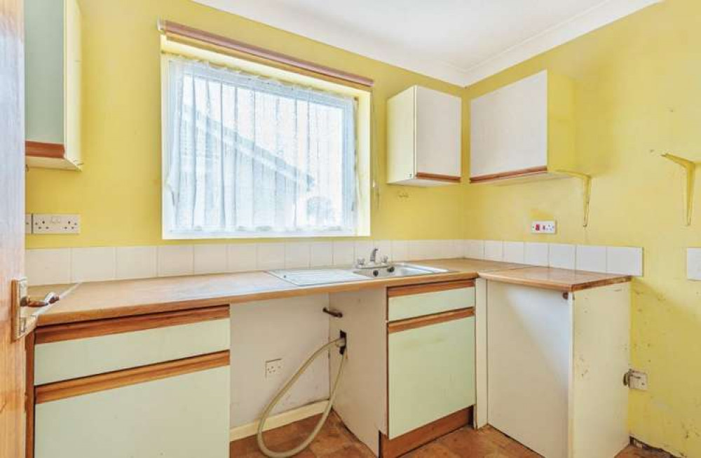 The kitchen has a range of units with spaces for appliances and a window above the sink (Bradleys)