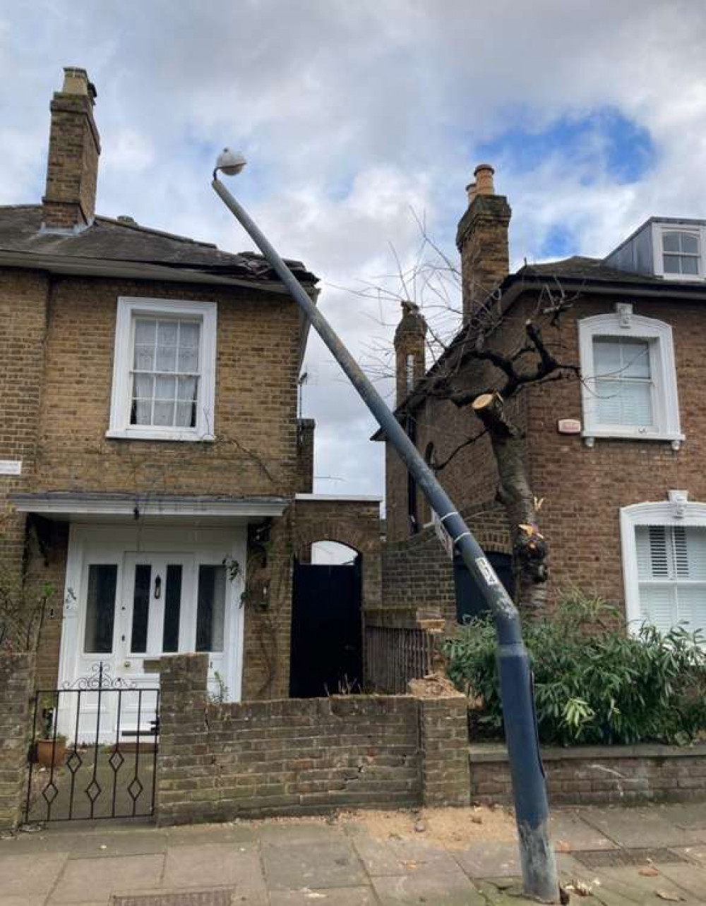 A lamppost on the road has been damaged by the tree