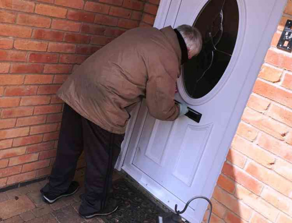 Deliver-you: A volunter post a lwaflet through a letterbox in Atherstone town centre