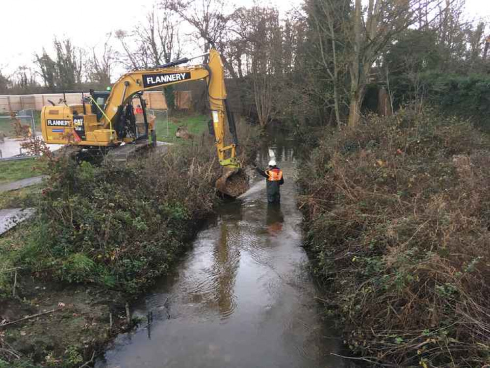 Workmen add stones to the riverbed to makes the water shallower.