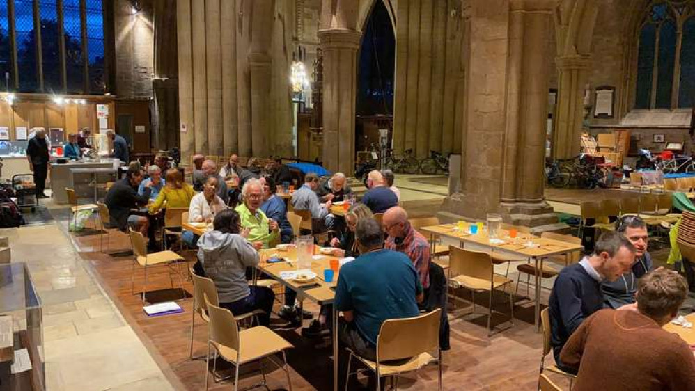 Cyclists sitting down to eat in St Wulfram's in Grantham – meal provided by food waste charity Second Helpings Stamford