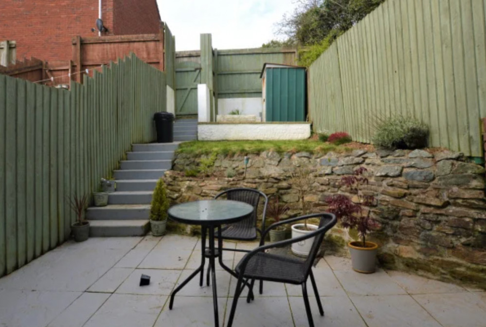 Enclosed garden with patio seating area. 