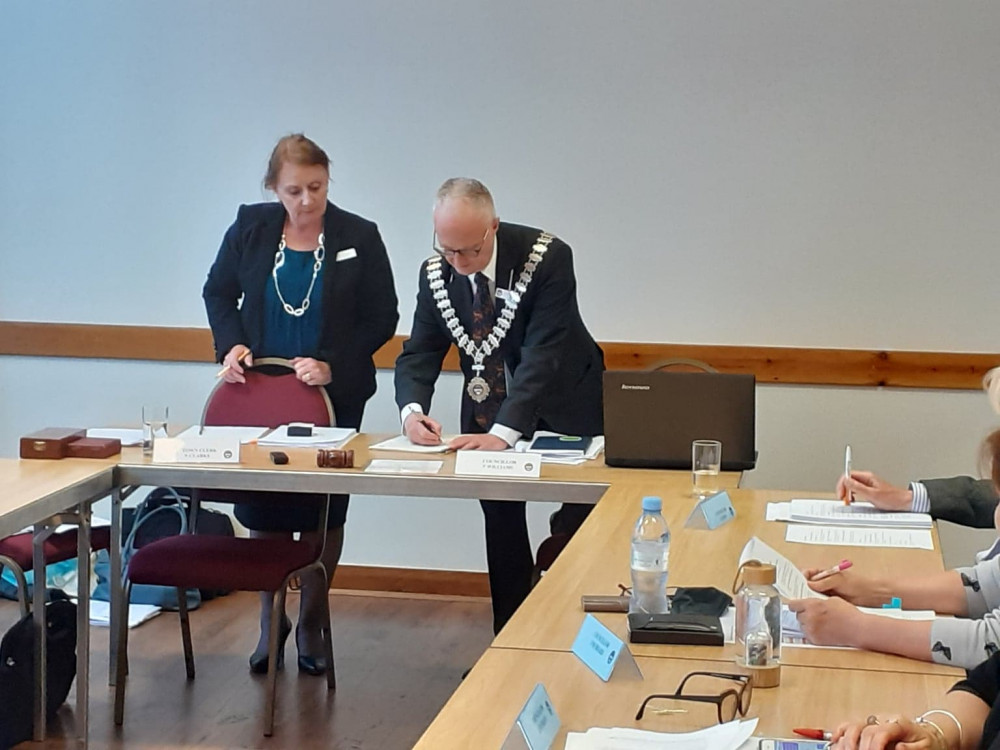 New chair, Cllr Phil Williams, signs the declaration of office in front of Alsager Town Council clerk, Nicola Clarke.