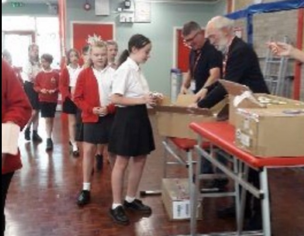 Parish council chairman Alastair McCraw handing out mugs to Brantham primary school pupils