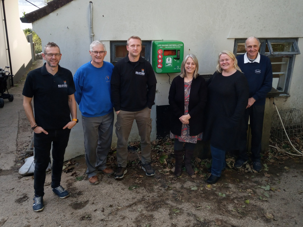 The defibrillator has been attached to the Changing Rooms of Axe Cliff Golf Club with easy view and access to the many thousands of Coastal Path walkers who have to pass the building on their walk to and fro Lyme Regis along the the Devon Coastal Path.  Pictured (from the left):ht : Ben Tucker , Restore ; Gerry Binmore; Andrew Davies, Restore; Suzy Seaby; Sharon Thorne; and Mike Wickens