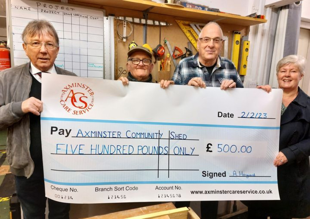 Axminster Care Service representatives Mervyn and Jacquie Symes present a cheque to Axminster Community Shed members