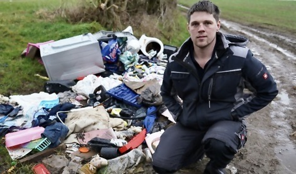 Will Oliver with the pile of rubbish at his farm. Photo: SWNS