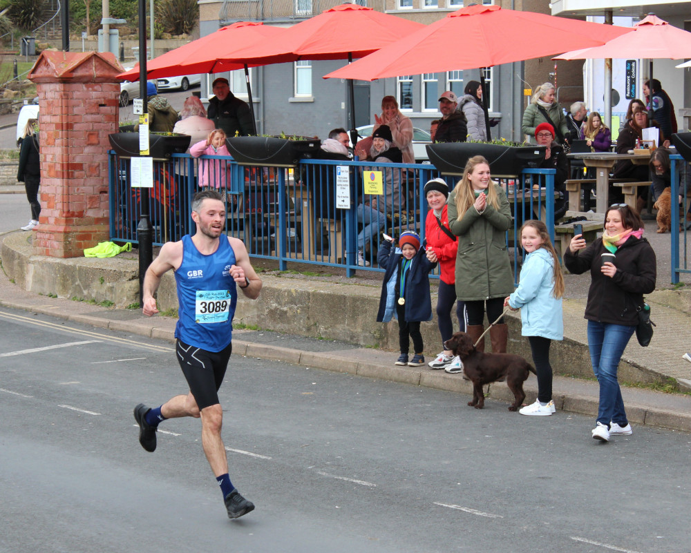 Local runner Ritchie Durrant is cheered by his family as he comes first in the Cub run