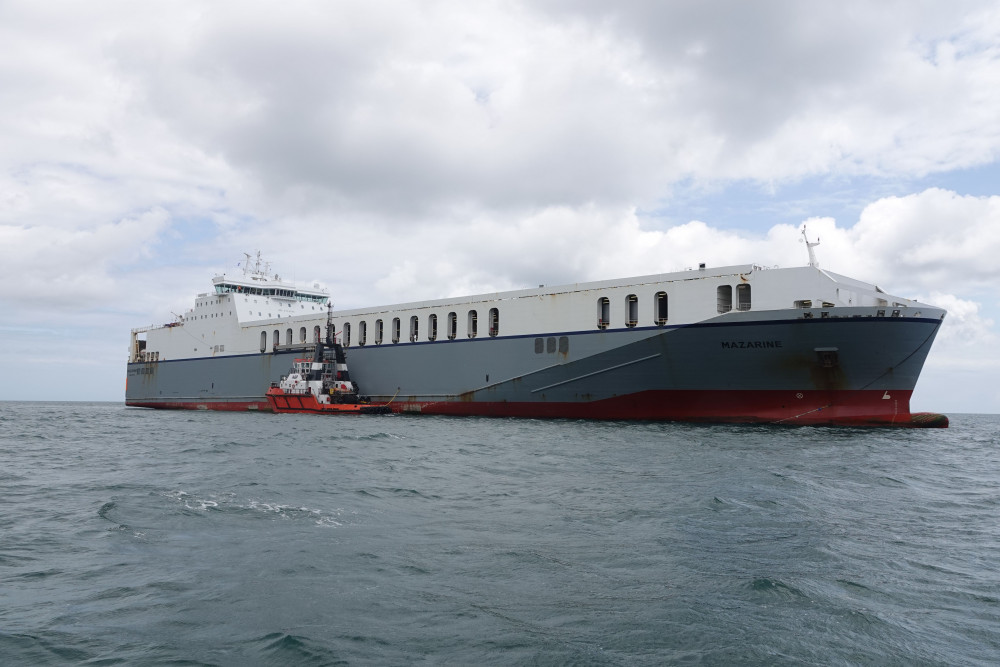 The large vessel 'MAZARINE' is now safe and pictured alongside the Falmouth tug 'Mercia' (Image: Falmouth Harbour)