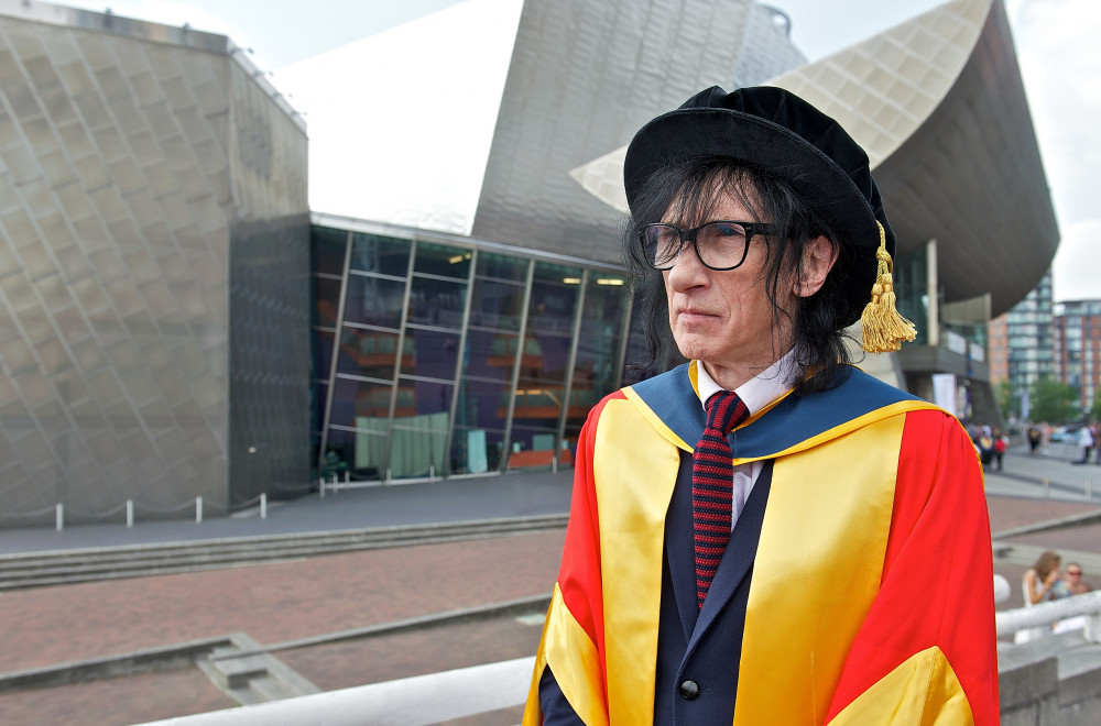 A rare photo of John Cooper Clarke without his iconic shades. (Image - CC 2.0 Unchanged University of Salford Press Office https://commons.wikimedia.org/wiki/File:John_Cooper_Clarke_receives_honorary_doctorate_in_2013.jpg)