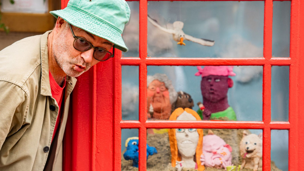 Artist Wilfrid Wood with Holiday Makers of Sidmouth piece in Market Square phone box (Sidmouth School of Art)