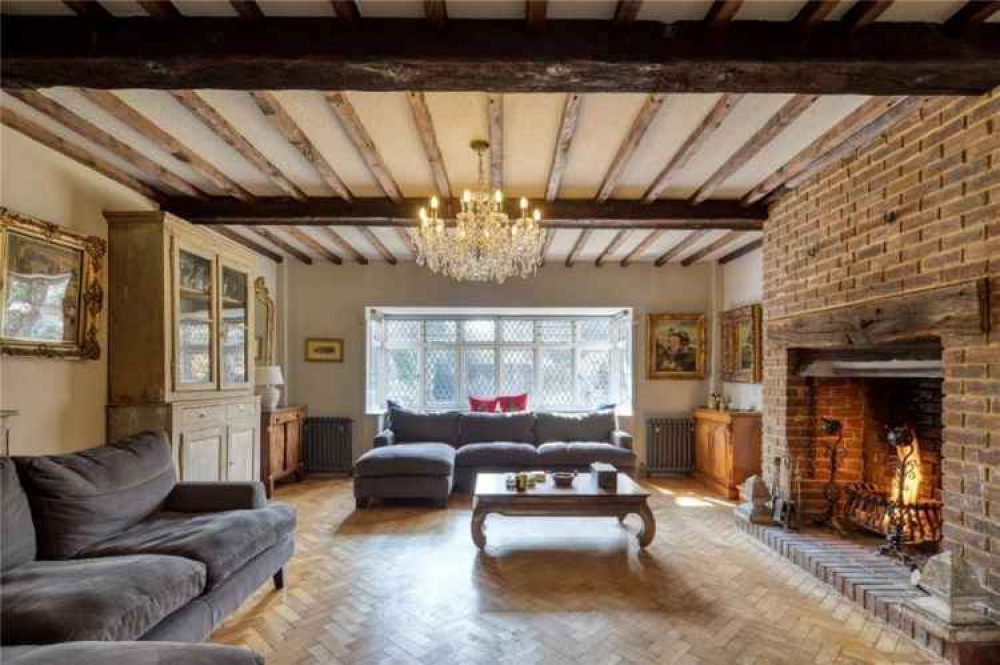 The historic living room features an inglenook fireplace, chandelier and exposed beams