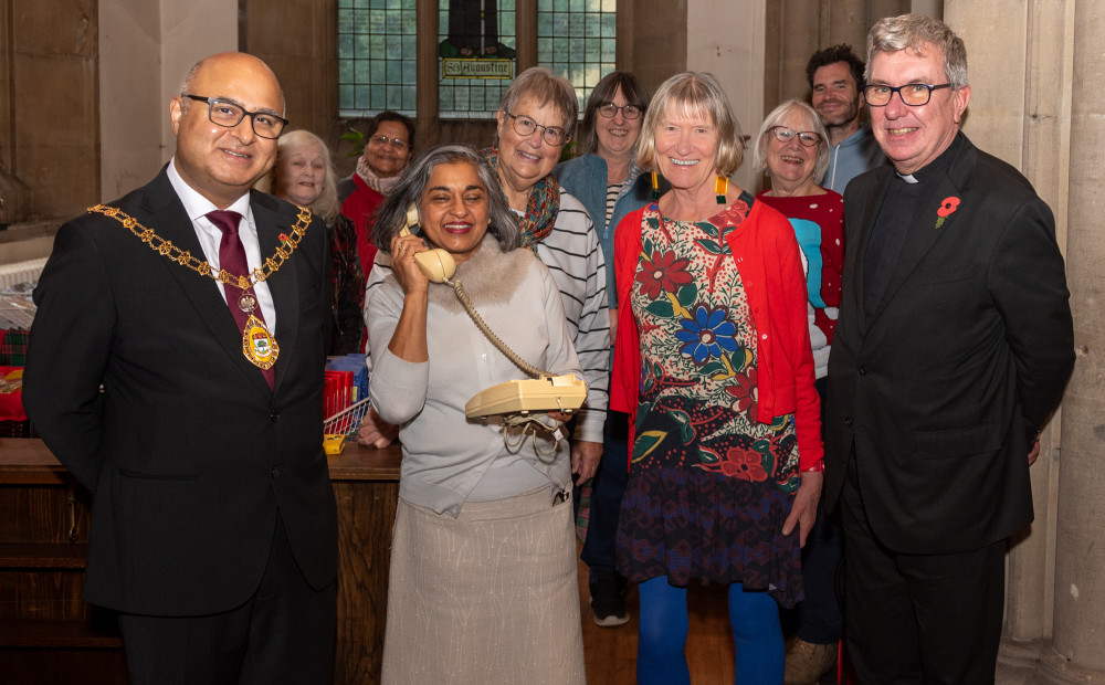 the Ealing Charity Christmas Shop are: (with phone) Ealing Hammersmith and Hounslow branch director Heena Johnson; (on her right) Ealing Mayor, Councillor Hitesh Taylor; (on her left) Sue Green, co-founder the Ealing Charity Christmas Shop and Father Richard Collins, Vicar of Parish Church of Christ the Saviour; along with Card Shop volunteers (image supplied).