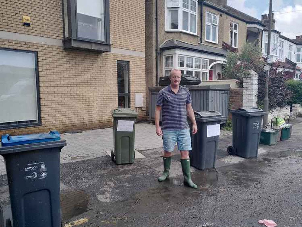 Nick Beazley with signs on his bins warning about the raw sewage. Streets near New Malden were affected (Credit: Tara O'Connor