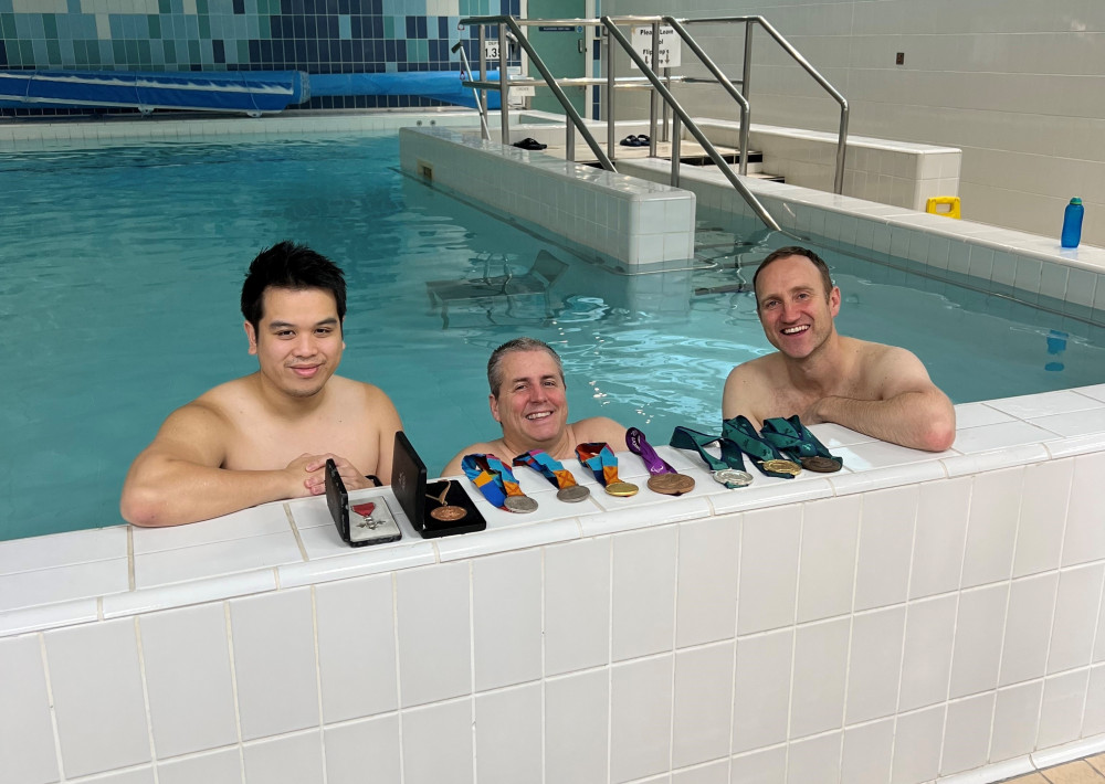 Matt Walker in the hydrotherapy pool (centre) with medals and physios Xav Nguyen and Andrew Hewitt (Image - Stockport NHSFT)