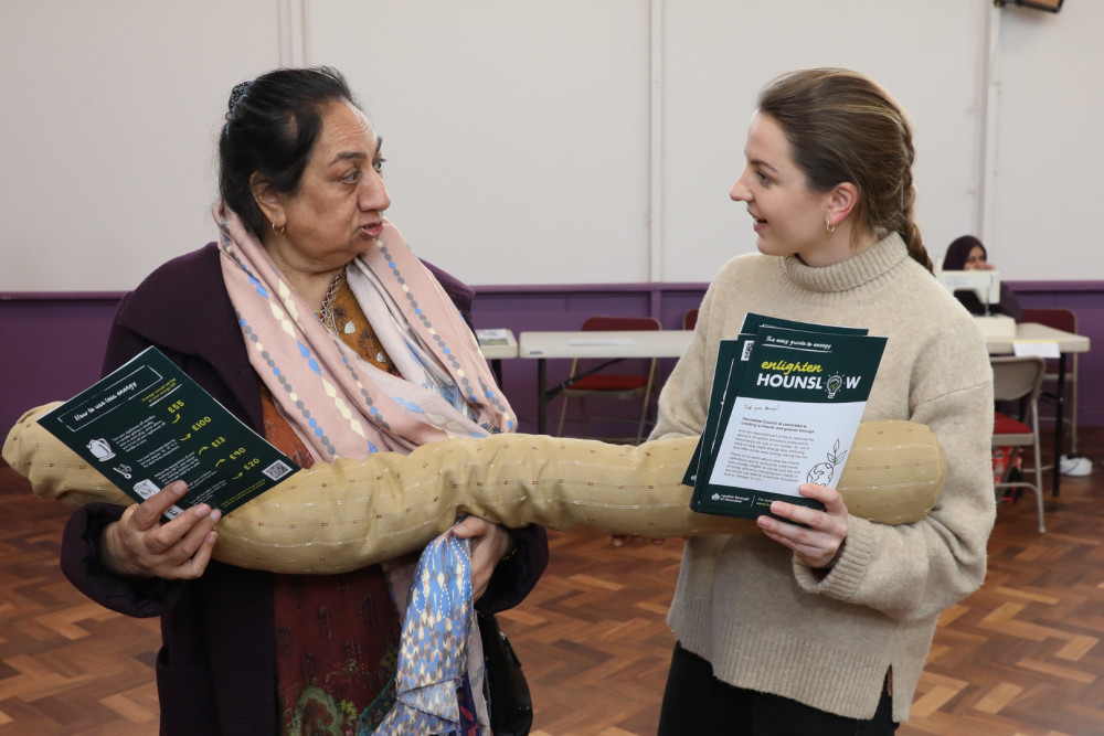 Resident receives an Enlighten Hounslow support-flyer while holding a draught excluder (credit: Hounslow Council).