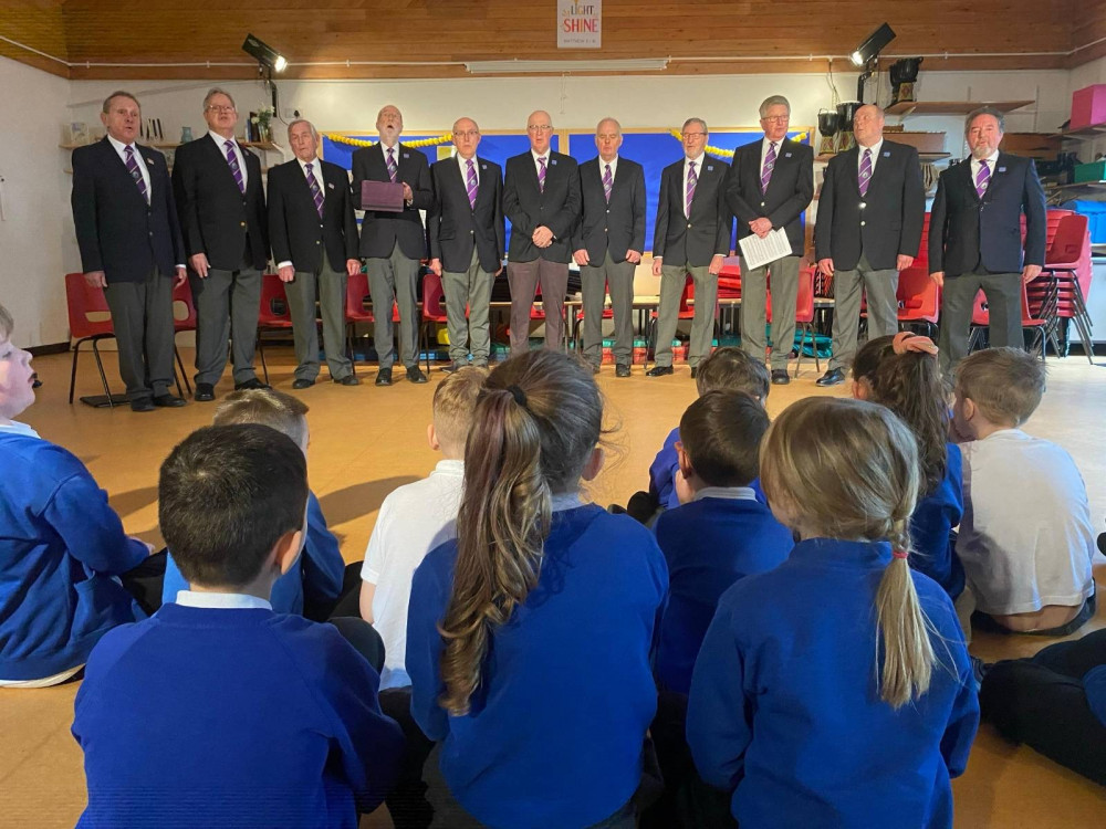 Pupils at St John's Infants watching Glastonbury Male Voice Choir perform at their school. 