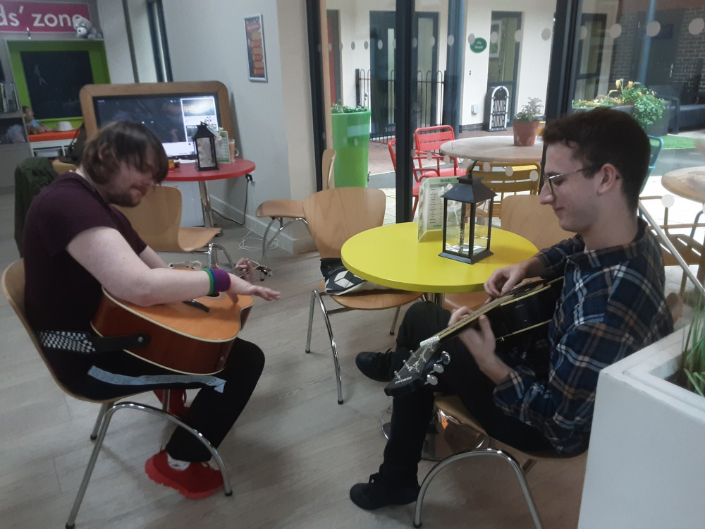 Musician David playing guitar with Alan, a resident at Woodside Care Village (image via WCS Care)