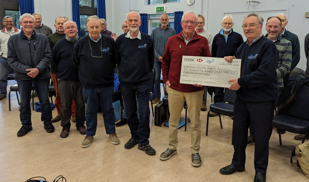 Concert organiser Roger White on right presenting cheque to Peter Hopwood, Chairman of SPSA and to the left Brue Boys Chairman John Longman flanked by members of the Brue Boys Choir (Submitted) 