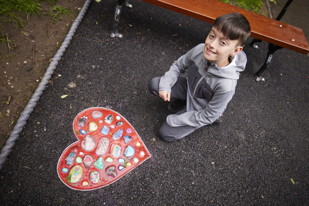 11-year-old Geo Wilson poses with a new artwork which celebrates his remarkable efforts during the Covid pandemic (Image - Stockport Council)