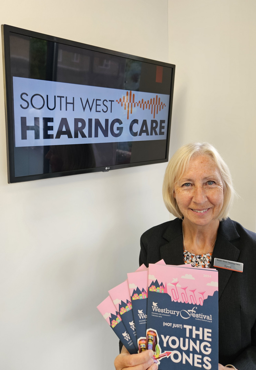 Sylvia Colby - Receptionist at South West Hearing Care's Westbury practice, holding aloft the Westbury Festival programmes