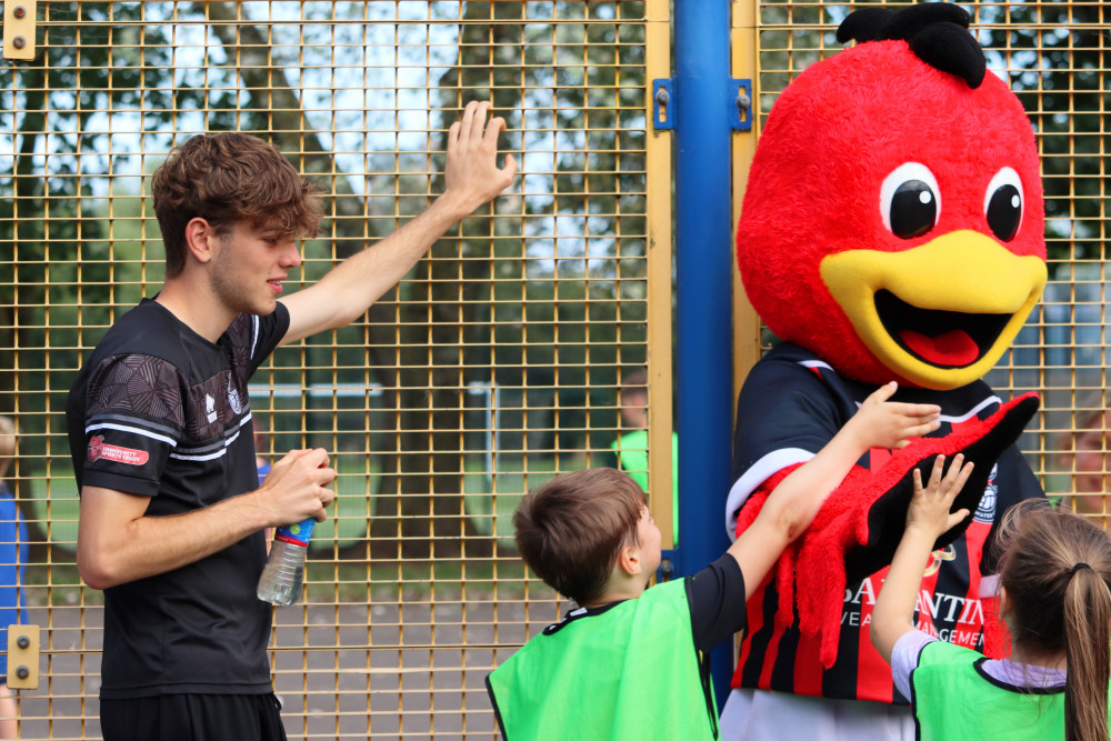 A young volunteer at Bridgwater Community Sports Trust watches over some children meeting the club's mascot 