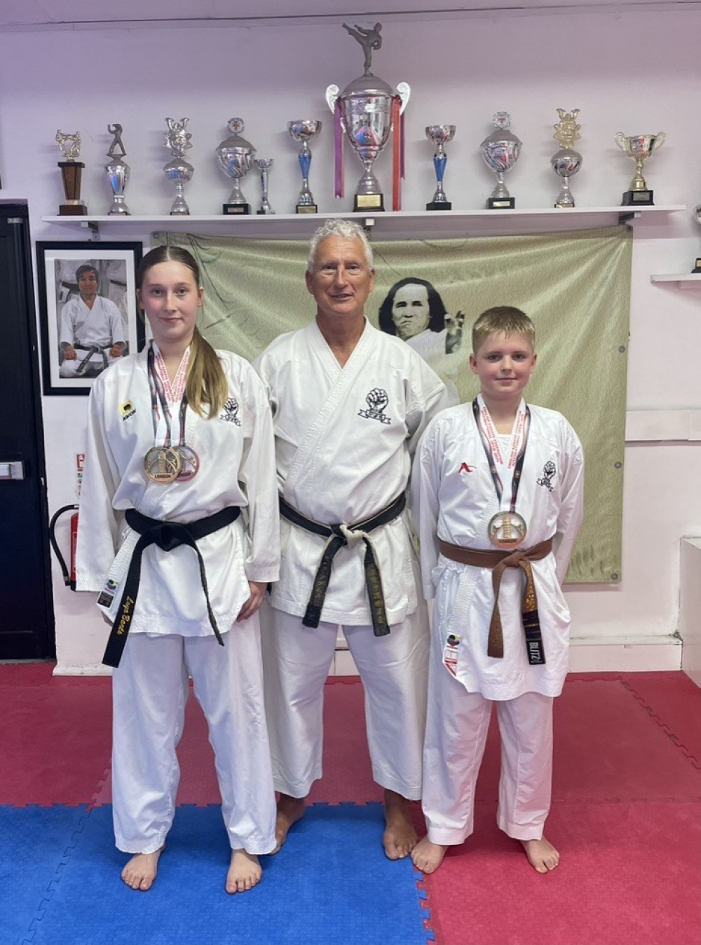 Leya Barts and Tomas Gudaitis both winning Gold in Kata (forms) at the EKF International Tournament, Leya also silver for Kumite (Fighting). The two are pictured with coach and instructor, Mark Adams 7th Dan.