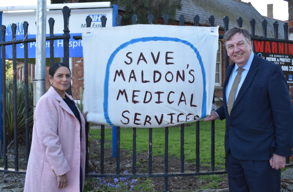 Dame Priti Patel and Sir John Whittingdale pose with a sign outside St Peter's Hospital, Spital Road. (Credit: Sir John Whittingdale)