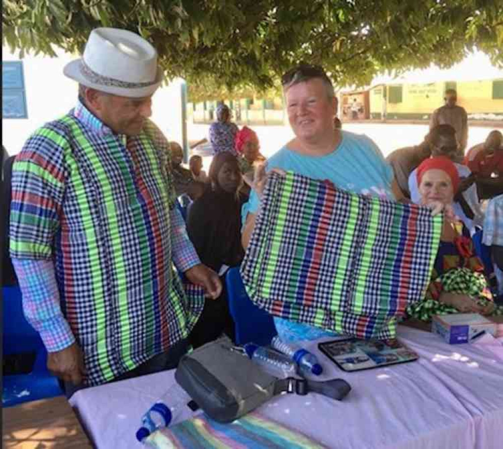 Julian and Wendy Andrews being presented with tops made out traditionally weaved fabric