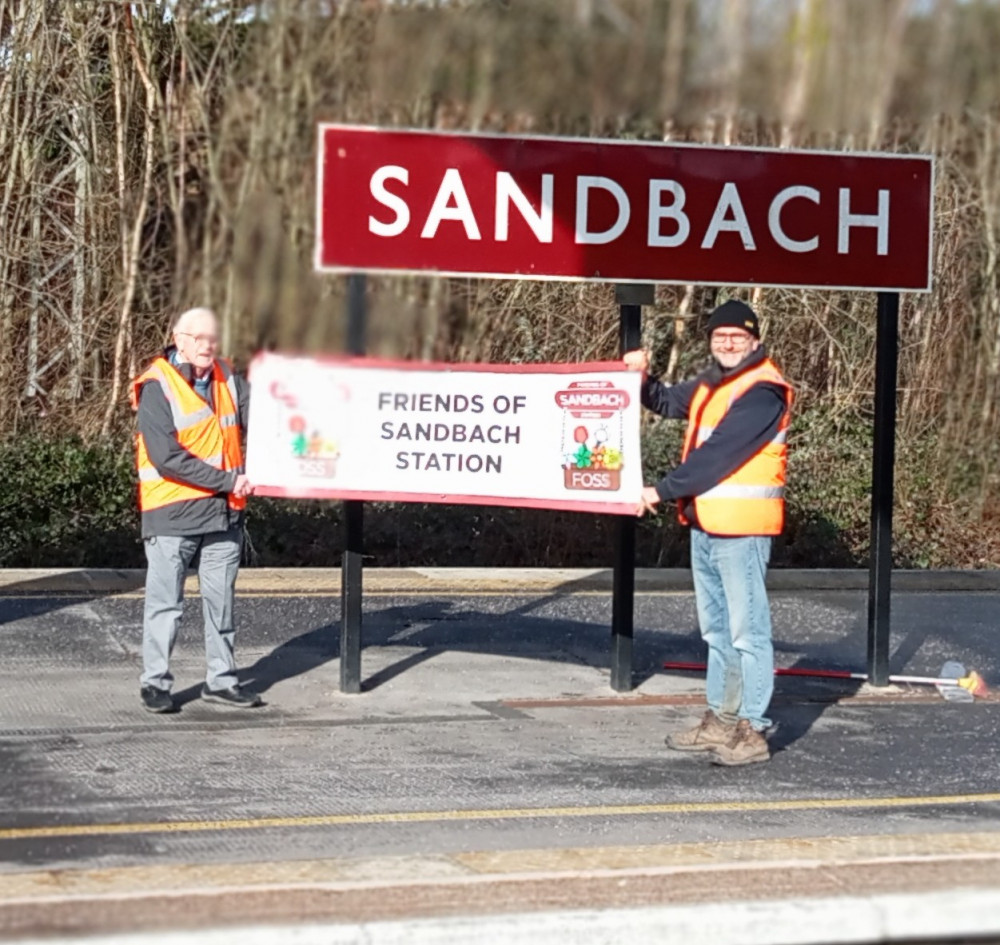 John Scarrott (left) hands over the Friends banner to Christian Shawcross with the original 1950s sign. (Photo: Friends of Sandbach Station)