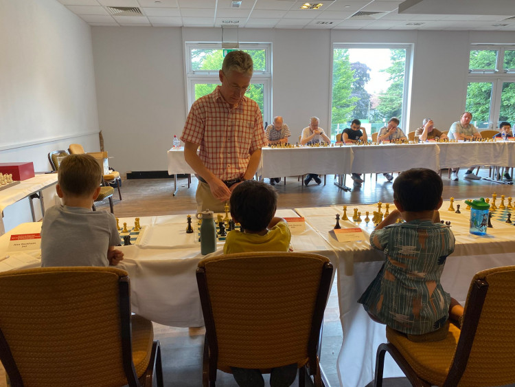 Taking it seriously! Michael Adams in play against 3 Coventry Chess Academy 5 year olds! (l-r, Alex Rackham, Sufyan Rashid and Riyaan Garnsworthy) (Photo: Paul Lam)