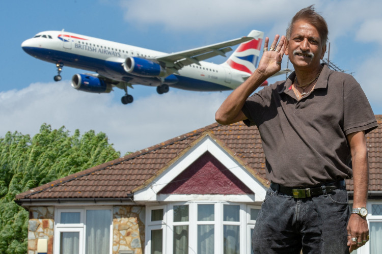 Harri Patel outside of his home in Myrtle Avenue, Heathrow with planes flying over (credit: Tony Kershaw/SWNS).