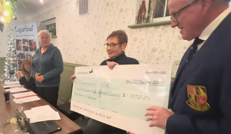 The cheque is handed over by Val Matthewson and Mike Ashton.